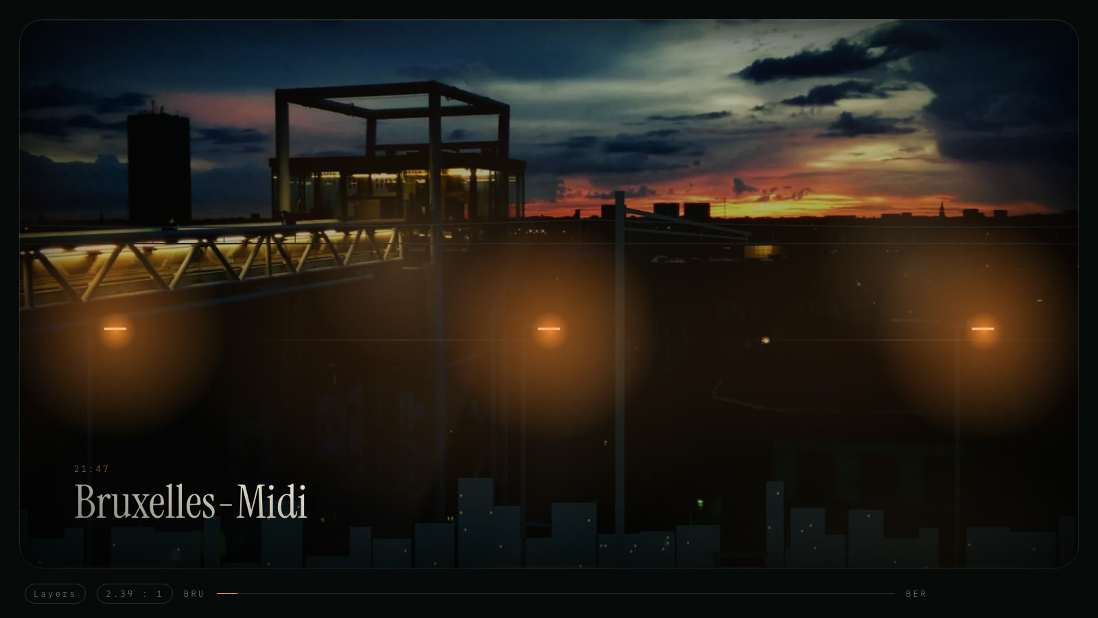 Bruxelles-Midi at 21:47: a lit footbridge and platform lamps against the last of the sunset