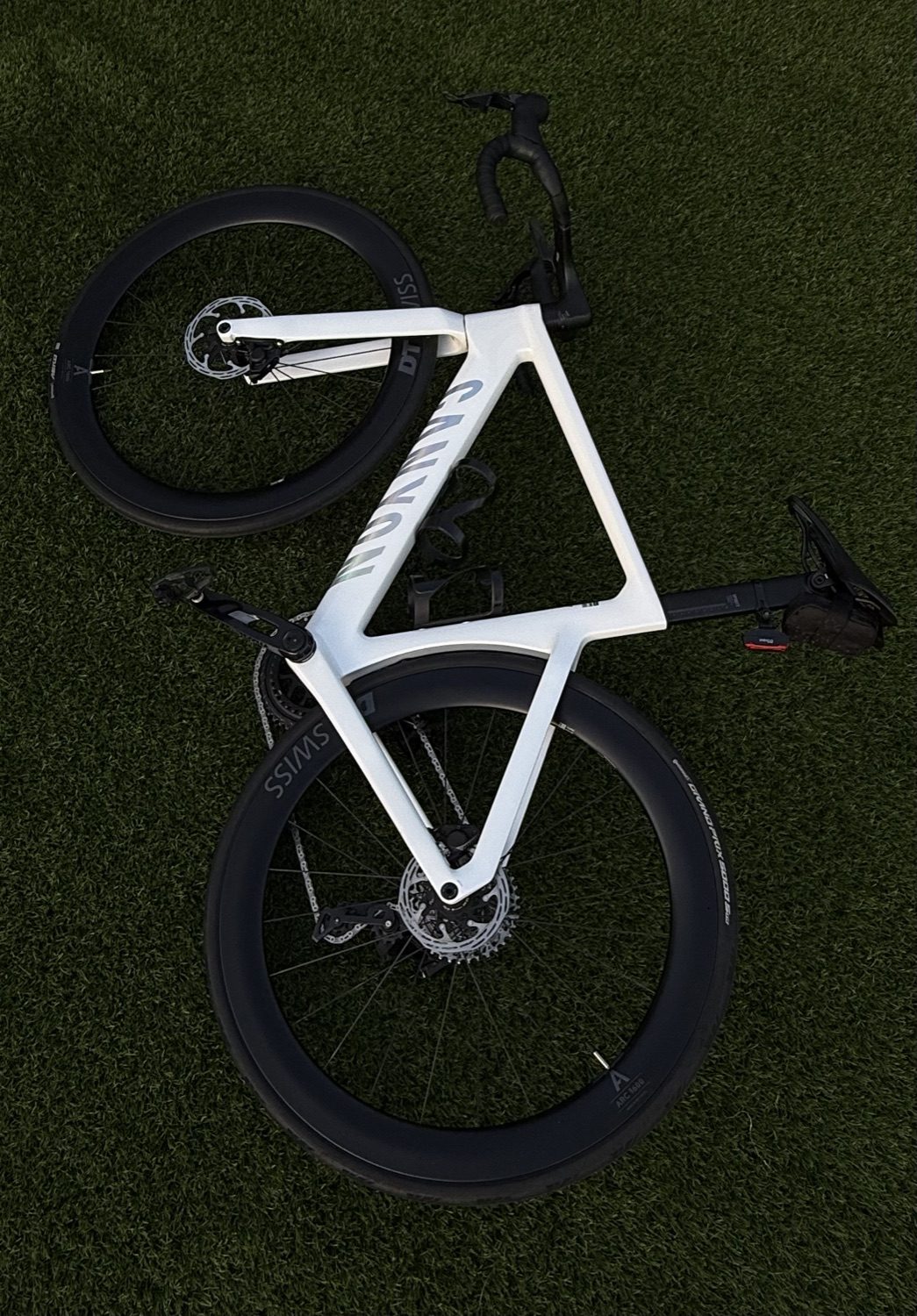 A white road bike lying on the grass, seen from above